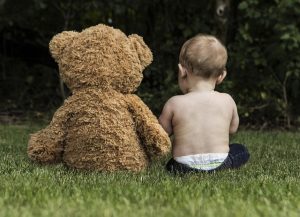 Teddybär und Baby sitzen nebeneinander