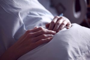 Hände liegen erschöpft auf Bettdecke