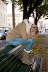 Verzweifelte Frau sitzt mit gesenktem Kopf auf Bank