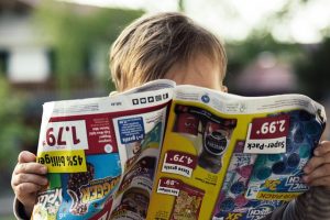 Ein Kind liest Zeitung mit Produktwerbung